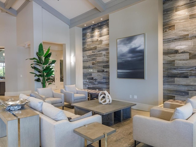 living room featuring beamed ceiling, a high ceiling, and light hardwood / wood-style flooring