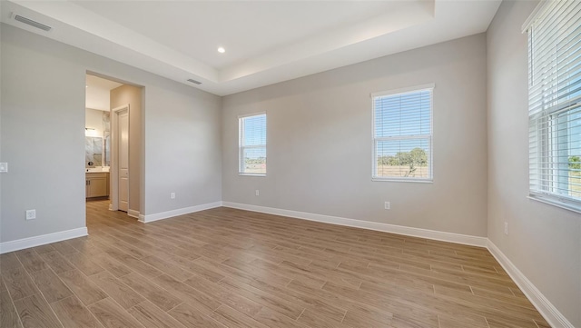 unfurnished room with a raised ceiling and light wood-type flooring