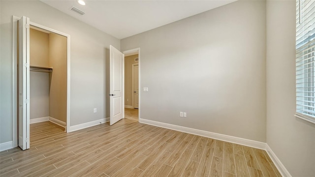 unfurnished bedroom featuring multiple windows, a closet, and light wood-type flooring