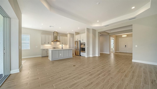 unfurnished living room with light hardwood / wood-style floors and a raised ceiling