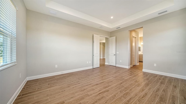 unfurnished bedroom with light hardwood / wood-style floors and a tray ceiling