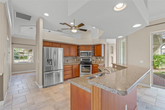 kitchen featuring ceiling fan, sink, light stone counters, decorative backsplash, and appliances with stainless steel finishes