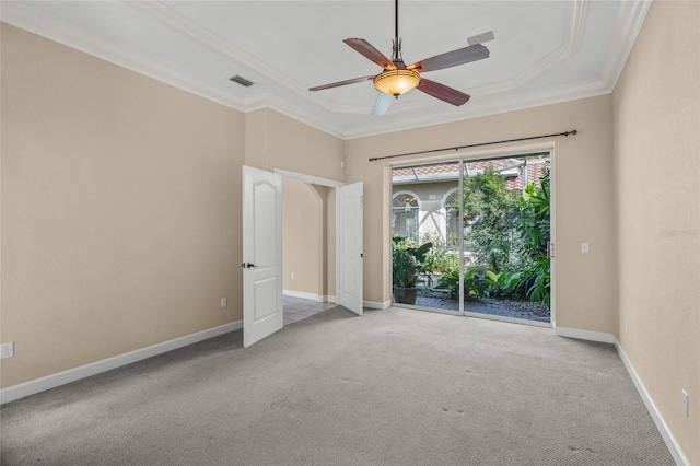 carpeted empty room with a raised ceiling, crown molding, and ceiling fan