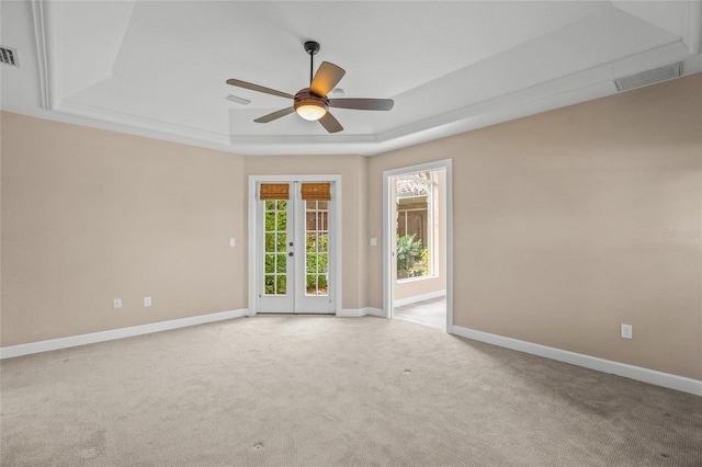 carpeted spare room featuring ceiling fan, french doors, and a tray ceiling