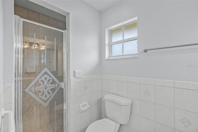 bathroom with toilet, a shower with door, and tile walls