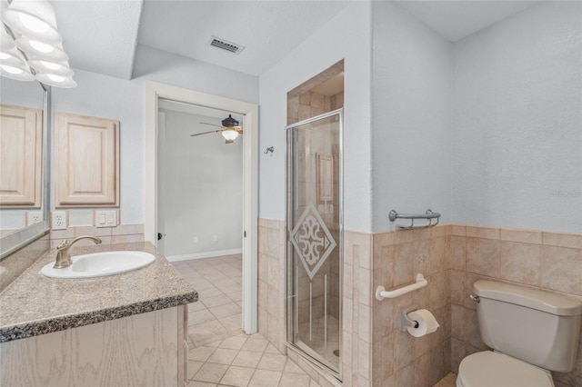 bathroom featuring vanity, tile patterned floors, toilet, tile walls, and walk in shower