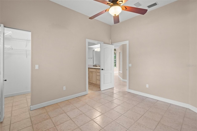 unfurnished bedroom featuring ceiling fan, ensuite bath, a walk in closet, and a closet