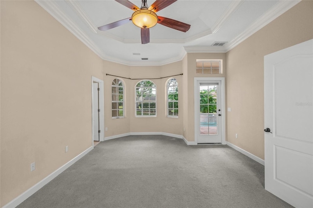 unfurnished room featuring ceiling fan, light colored carpet, ornamental molding, and a tray ceiling