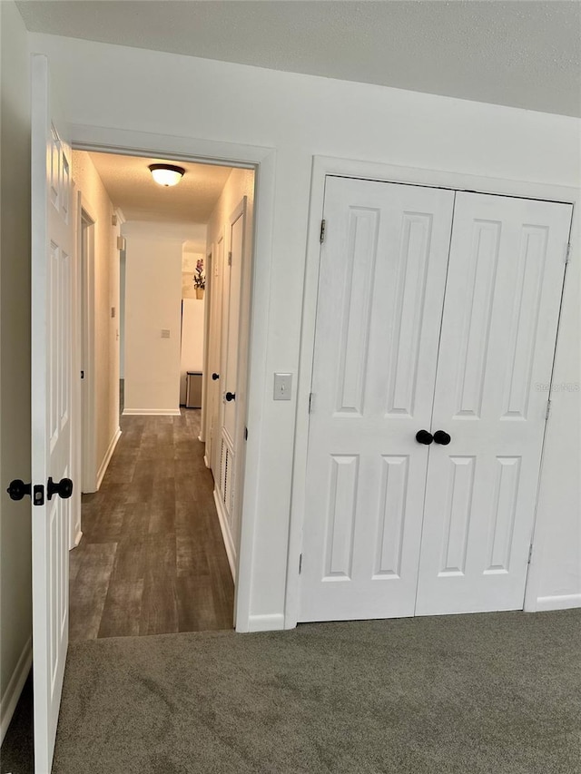 hall with dark colored carpet