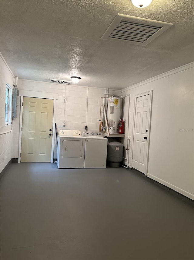 laundry area with a textured ceiling, water heater, and washing machine and clothes dryer