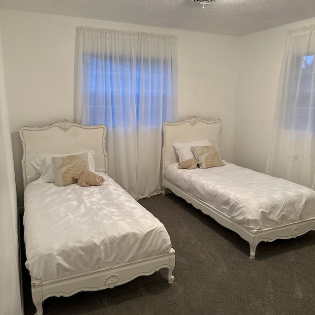 bedroom with dark colored carpet and a textured ceiling