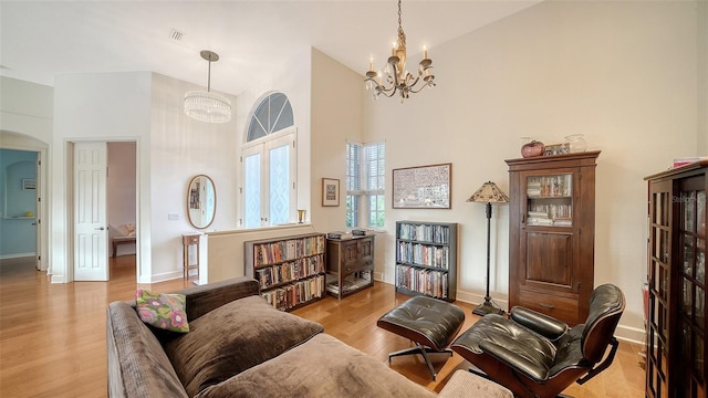 living area featuring high vaulted ceiling, a chandelier, and light wood-type flooring