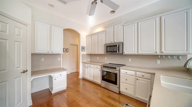 kitchen with ceiling fan, sink, stainless steel appliances, white cabinets, and light wood-type flooring