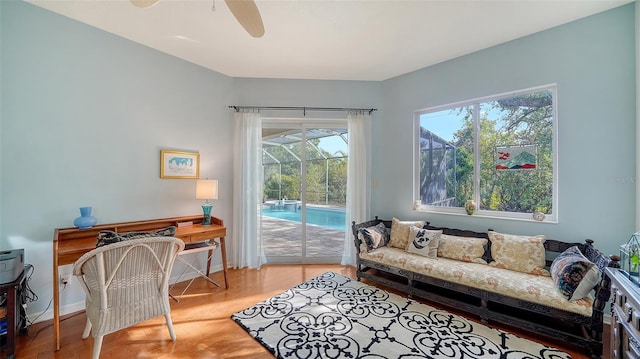 sitting room featuring ceiling fan, wood-type flooring, and a swimming pool