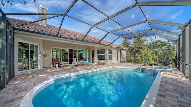 view of swimming pool featuring glass enclosure, a patio area, and an in ground hot tub