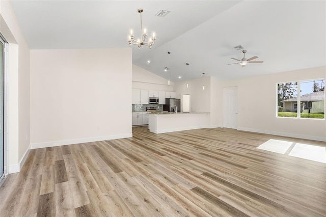 unfurnished living room with high vaulted ceiling, ceiling fan with notable chandelier, and light wood-type flooring