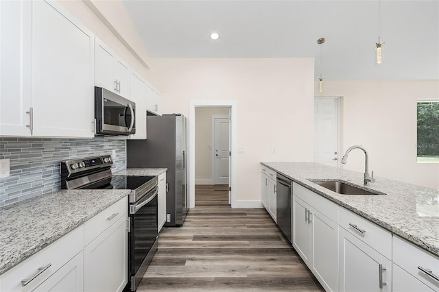 kitchen with appliances with stainless steel finishes, light stone counters, decorative light fixtures, white cabinets, and dark hardwood / wood-style floors