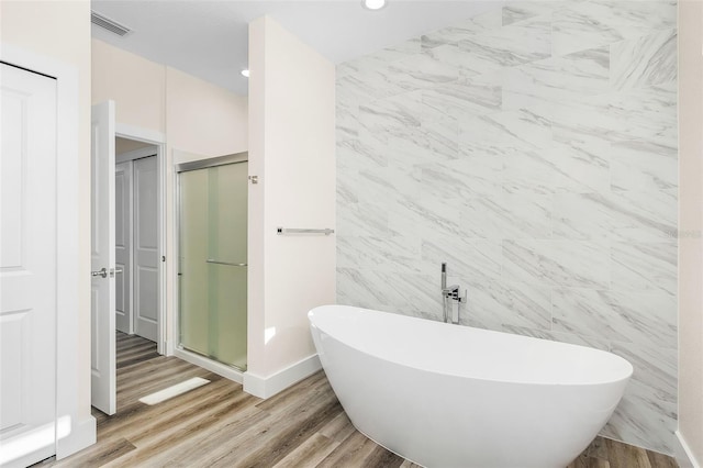 bathroom with independent shower and bath, tile walls, and hardwood / wood-style flooring