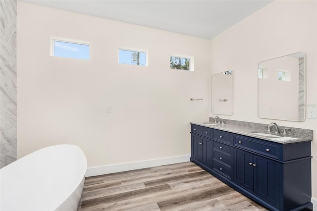 bathroom with a wealth of natural light, a washtub, vanity, and wood-type flooring