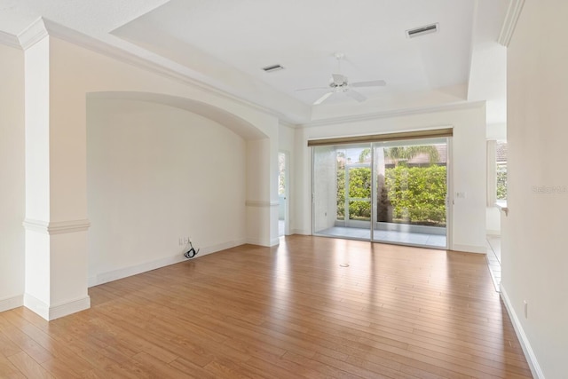 unfurnished room with light hardwood / wood-style floors, a raised ceiling, ceiling fan, and ornamental molding