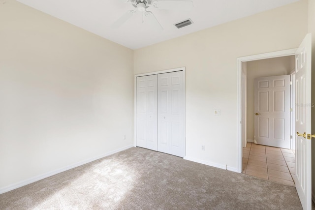 unfurnished bedroom featuring ceiling fan, light colored carpet, and a closet