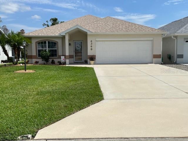 ranch-style home with a garage and a front lawn