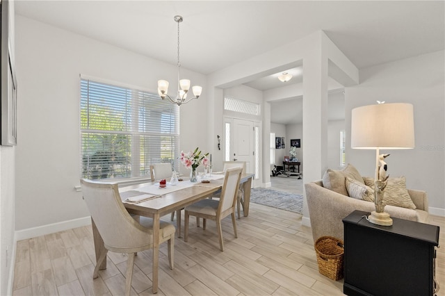 dining area featuring light wood-style floors, baseboards, and an inviting chandelier