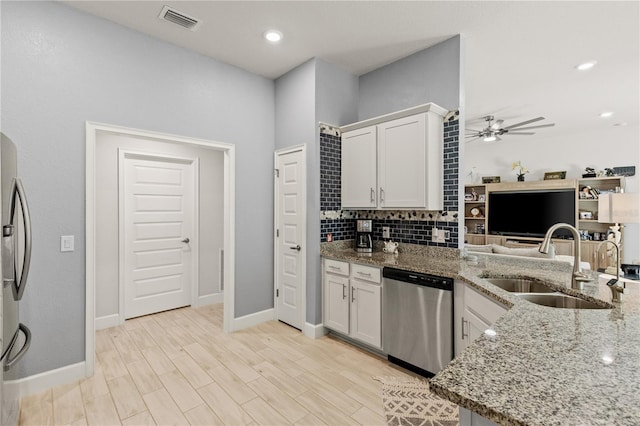 kitchen with stone counters, a sink, visible vents, appliances with stainless steel finishes, and backsplash