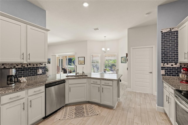 kitchen featuring tasteful backsplash, a peninsula, stainless steel appliances, light wood-style floors, and a sink