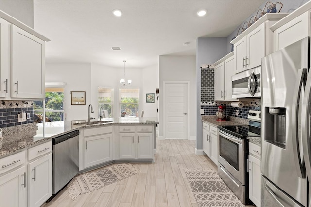 kitchen featuring recessed lighting, appliances with stainless steel finishes, white cabinetry, a sink, and a peninsula