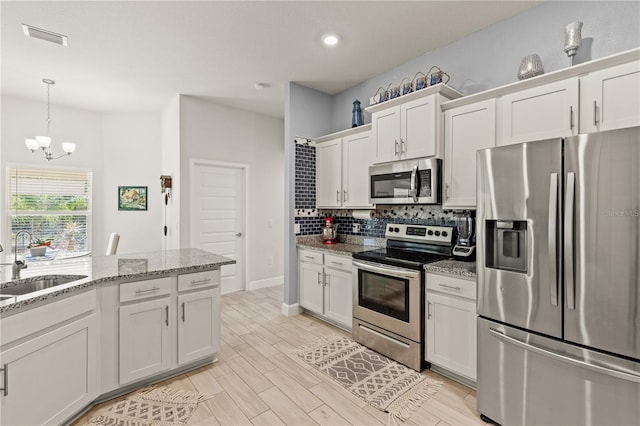 kitchen featuring a sink, stainless steel appliances, light wood-style floors, white cabinetry, and backsplash