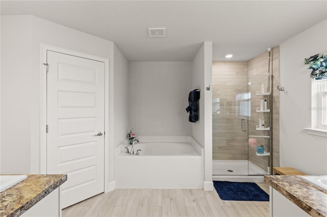 bathroom with visible vents, a shower stall, vanity, wood finished floors, and a bath