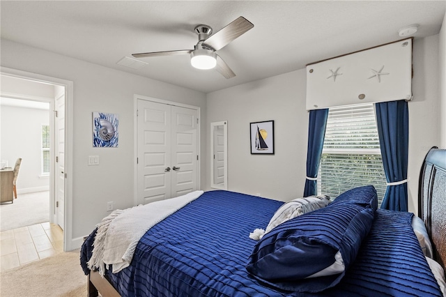 bedroom featuring a closet, light carpet, ceiling fan, and baseboards