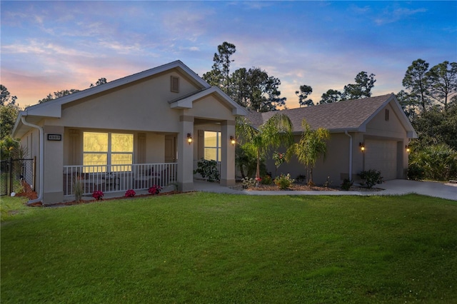 ranch-style house featuring a garage, driveway, covered porch, a yard, and stucco siding