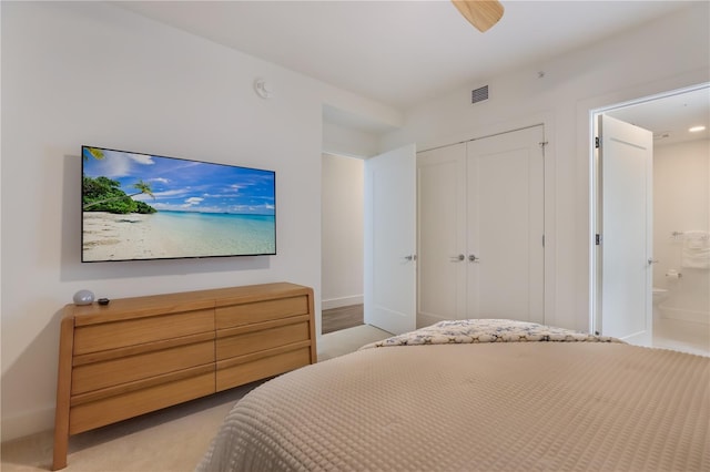 bedroom featuring ceiling fan, light colored carpet, connected bathroom, and a closet