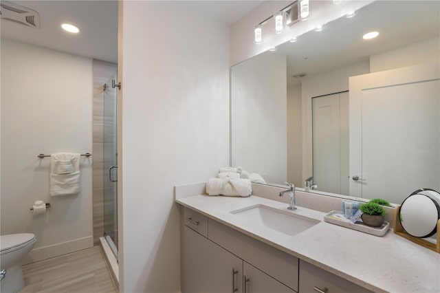 bathroom with hardwood / wood-style floors, vanity, toilet, and a shower with door