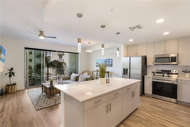 kitchen featuring stainless steel appliances, ceiling fan, light hardwood / wood-style flooring, a kitchen island, and hanging light fixtures