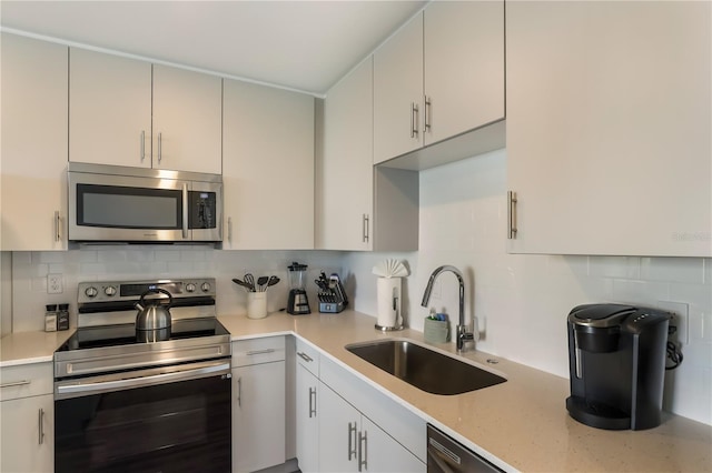 kitchen featuring tasteful backsplash, white cabinetry, sink, and stainless steel appliances