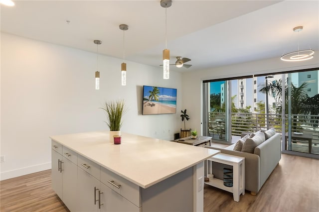 kitchen featuring a center island, white cabinets, ceiling fan, decorative light fixtures, and light hardwood / wood-style floors