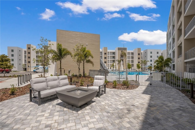 view of patio with a community pool and an outdoor living space with a fire pit