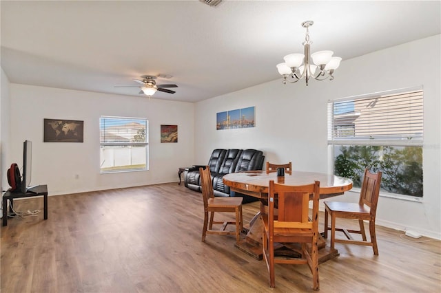 dining area with ceiling fan with notable chandelier and wood-type flooring