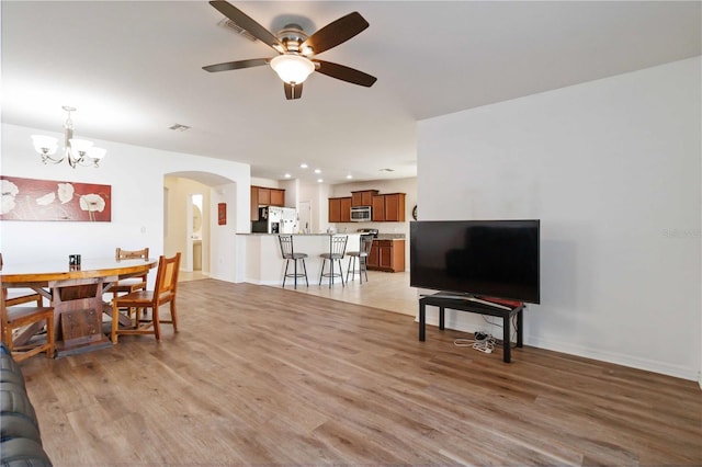 living room with light hardwood / wood-style floors and ceiling fan with notable chandelier