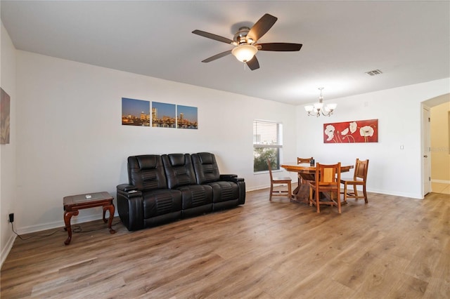 living room featuring ceiling fan with notable chandelier and hardwood / wood-style flooring