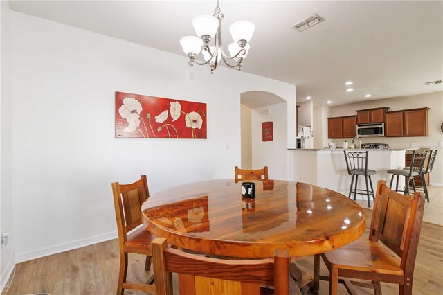 dining space with a chandelier and light hardwood / wood-style flooring