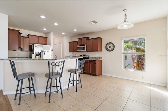 kitchen featuring a breakfast bar area, light stone countertops, stainless steel appliances, and decorative light fixtures