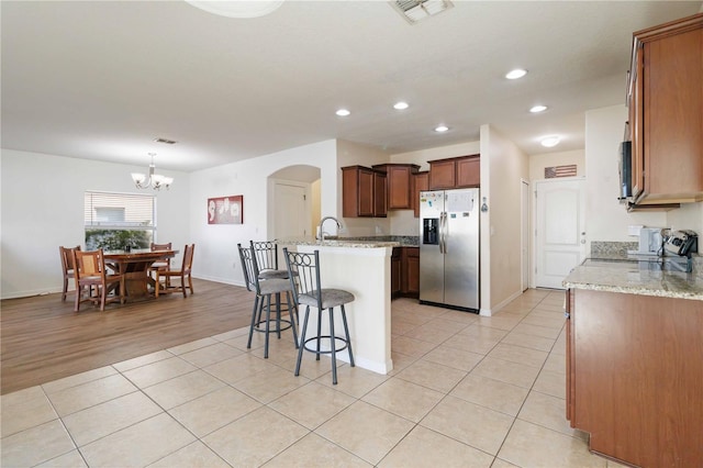 kitchen featuring light stone countertops, appliances with stainless steel finishes, a notable chandelier, light hardwood / wood-style floors, and hanging light fixtures