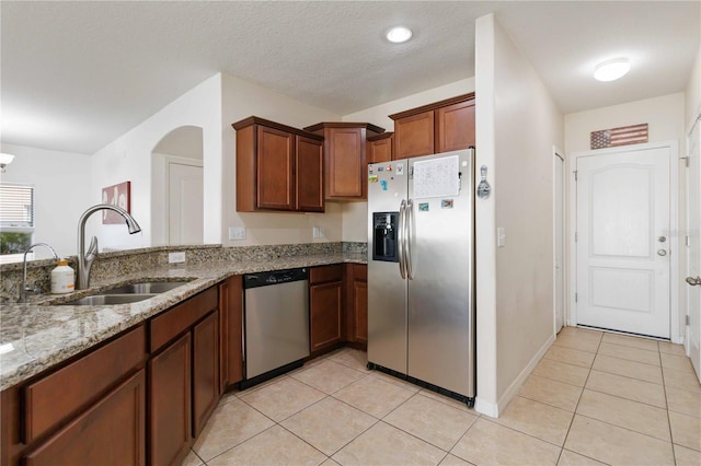 kitchen featuring light tile patterned flooring, appliances with stainless steel finishes, light stone counters, and sink