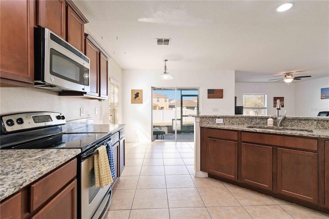 kitchen with sink, ceiling fan, appliances with stainless steel finishes, decorative light fixtures, and light stone counters