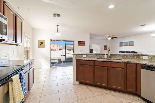 kitchen featuring ceiling fan, sink, stainless steel appliances, light stone counters, and decorative light fixtures