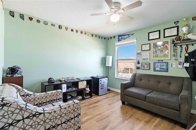 living room featuring ceiling fan, light wood-type flooring, and a textured ceiling